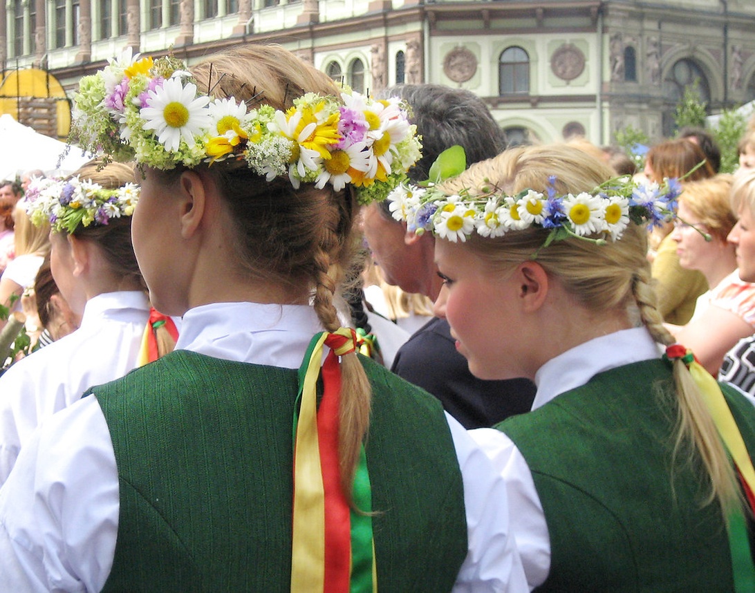 Personer med traditionella svenska blomsterkransar och folkdräkter under ett midsommarfirande.
